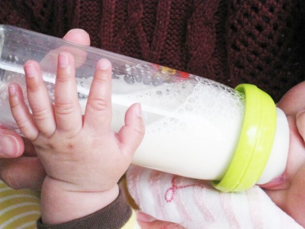 自分で哺乳瓶を持ってミルクを飲む赤ちゃん